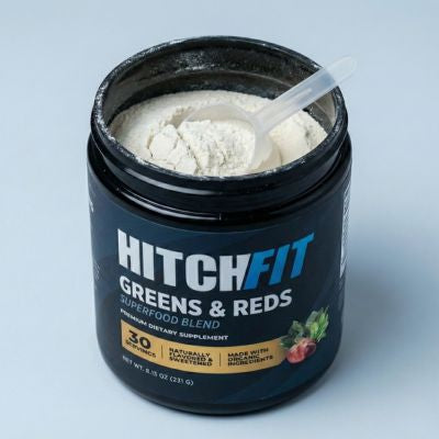 Open tub of Hitch Fit Greens & Reds Superfood Blend showing a plastic scoop in the daily super greens powder supplement, designed specifically for athletes