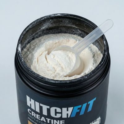 Unflavored creatine monohydrate powder supplement showing a 5g scoop inside an open container